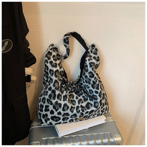 Detailansicht der flauschigen Leopard-Einkaufstasche mit Schleife auf einem Metallkoffer