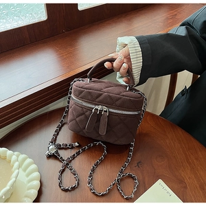 Detail view of brown quilted suede bucket bag with leather chain strap and silver hardware