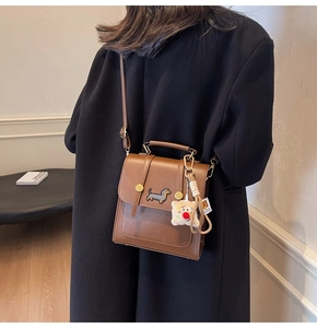 Detail of vintage brown crossbody bag with dachshund embroidery and teddy bear charm