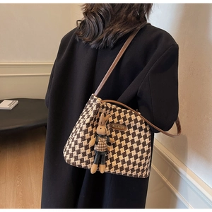 Detail of checkered tote bag with brown straps and cute rabbit charm on a model