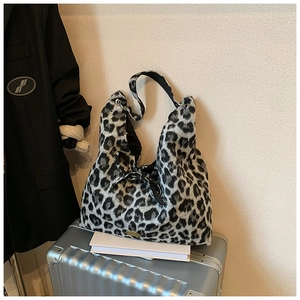 Nahaufnahme der Leopardenmuster-Plüschtasche mit Schleife auf silbernem Koffer