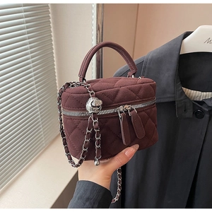 Detail of dark burgundy quilted velvet bucket bag with silver chain and dual zippers