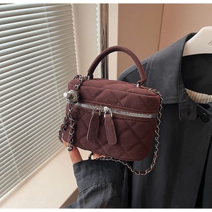 Close-up of deep red quilted velvet bucket bag with silver chain strap and dual zippers