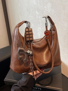Brown hobo shoulder bag with chocolate pendant and beads decoration in a hand-held view