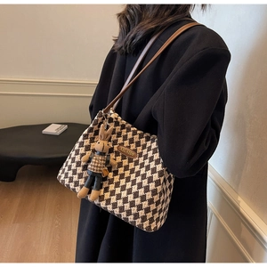 Detail of checkered shoulder bag with plush bunny charm and brown leather straps