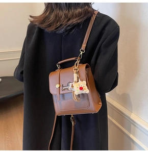Close-up of brown vintage backpack featuring dachshund embroidery and cute bear pendant