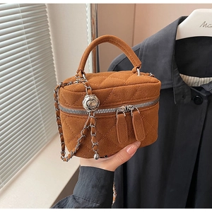 Close-up of caramel quilted suede bucket bag with silver chain and dual zippers
