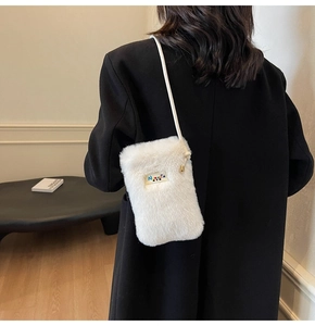 Petit sac bandoulière en fausse fourrure blanche porté sur un manteau noir d'hiver