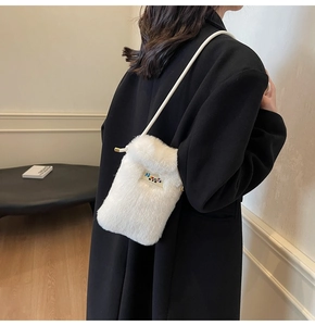 Vue détaillée d'un mini sac à bandoulière blanc en fausse fourrure sur un manteau noir