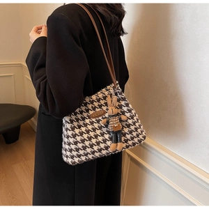 Detail of houndstooth tote bag with brown leather straps and a cute rabbit charm