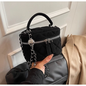 Detailed view of black quilted vanity bag with silver chain and metal ball adjuster