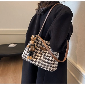 Close-up of houndstooth tote bag with brown leather strap and a cute bunny charm