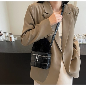 Nahaufnahme der schwarzen Stepptasche mit Plüschgriff und herzförmigen Metallanhängern