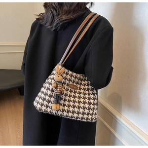 Detail of houndstooth tote bag with brown leather strap and cute bunny doll charm