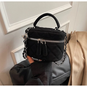 Detail of black quilted velvet bucket bag with silver chain and top handle