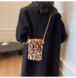Détail d'un sac bandoulière en peluche léopard porté avec un élégant manteau noir