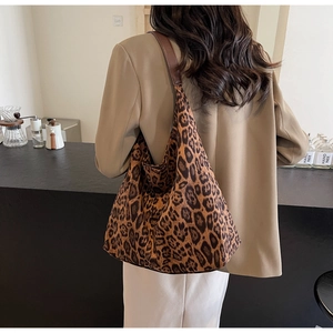 Détail d'un grand sac cabas léopard avec bandoulière en cuir marron dans un café
