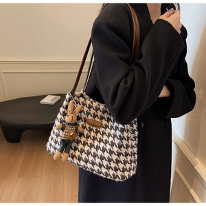 Brown houndstooth tote bag with leather strap and cute rabbit doll pendant on a model