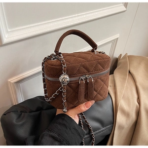 Close-up of brown quilted bucket bag with chain strap and silver metal details