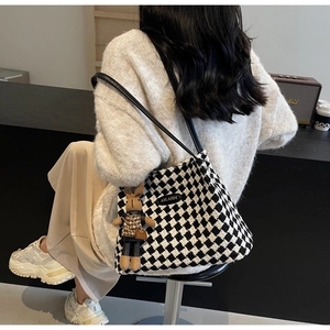 Detail of checkered knit tote bag with rabbit charm and leather shoulder straps
