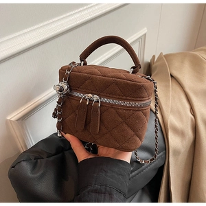 Detailed view of dark brown quilted suede bucket bag with chain strap and dual zippers