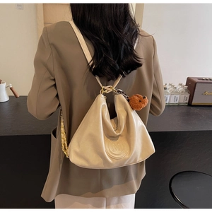 Detail of cream-white backpack with M-embossed texture and a cute brown teddy bear charm