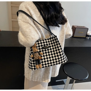 Detail of checkered knit tote bag with brand logo label and cute bunny charm accessory