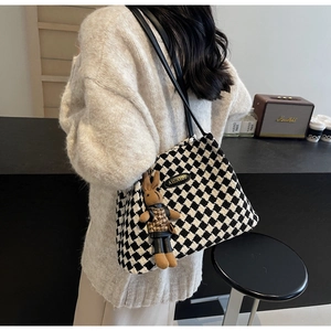 Detail of checkered tote bag with plush bunny charm and thin leather shoulder straps
