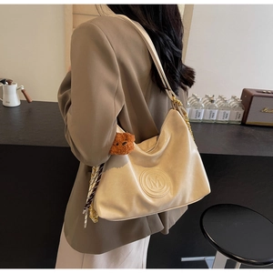 Detail of cream white leather shoulder bag with M logo, bear charm and polka dot scarf