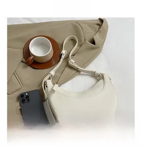 Dettaglio borsa a mezzaluna beige in pelle a grana con tracolla regolabile