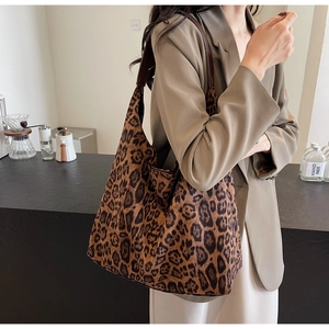 Sac fourre-tout chic en toile à imprimé léopard porté par un mannequin dans un café chic