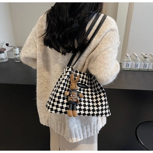 Detail of checkered tote bag with cute plush rabbit charm and slim leather straps