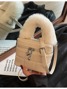 Gesteppte cremefarbene Lederbox-Tasche mit Kunstpelzgriff und Herz-Reißverschluss im Spiegel