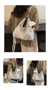 Detail of silver metallic textured shoulder bag featuring butterfly charms and plush cloud pendant