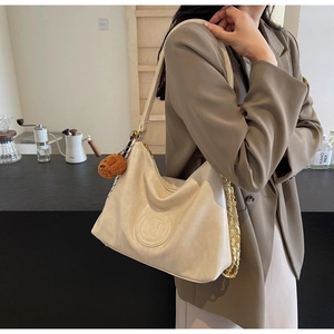 Detail of cream leather shoulder bag with embossed M logo and brown bear charm
