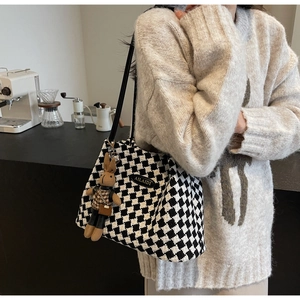 Detail of checkered tote bag with a cute plush rabbit charm in a cozy cafe setting