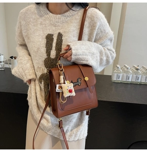 Detail of vintage brown shoulder bag with dachshund embroidery and teddy bear charm