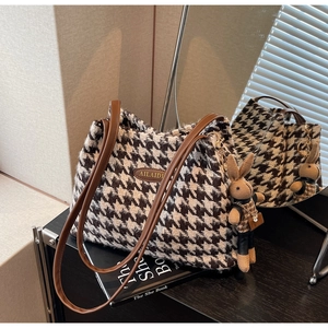 Macro shot of houndstooth tote bag with brown faux leather straps and rabbit plush charm