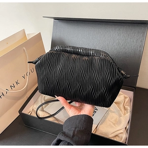 Detail der schwarzen Faltentasche mit eleganter Geschenkbox und weißer Tragetasche