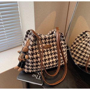 Detailed shot of houndstooth tweed tote bag with leather logo and brown rabbit charm
