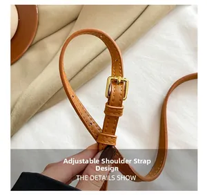 Gros plan sur la bandoulière réglable en cuir marron avec boucle en métal doré