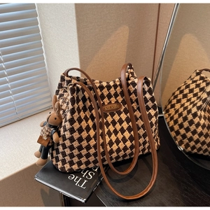 Detail of checkered tote bag with brown leather straps and cute rabbit charm
