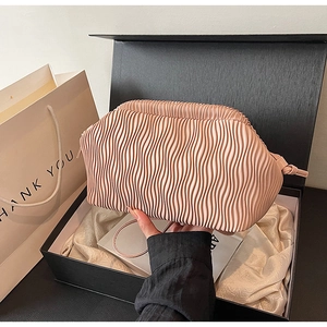 Makrodetail einer rosa Falten-Cloud-Tasche mit vertikaler Wellentextur und Seidenfinish