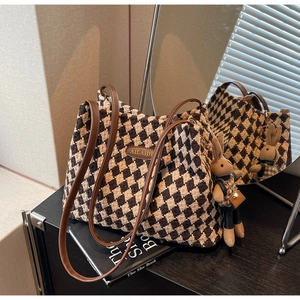 Close-up of checkered tote bag with leather handles and a cute bunny pendant charm
