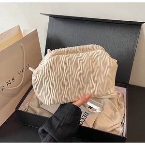 Detailansicht der cremeweißen Plissee-Tasche in einer schwarzen Geschenkbox