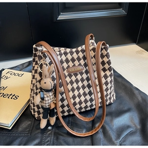 Detail of checkered tweed tote bag with gold metal logo and cute rabbit plush charm