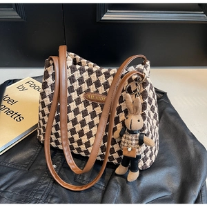 Detail of vintage houndstooth tote bag with brown leather strap and rabbit charm