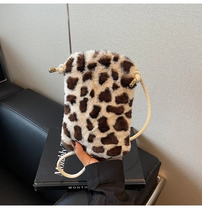 Détail d'un petit sac bandoulière en peluche léopard avec finitions dorées et sangle blanche