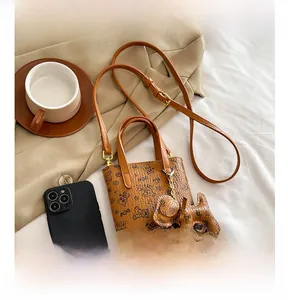 Détail du petit sac pour téléphone en cuir marron avec motifs d'ours et boucle dorée chic