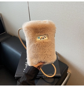 Gros plan du sac bandoulière en fausse fourrure beige avec étiquette et fine sangle